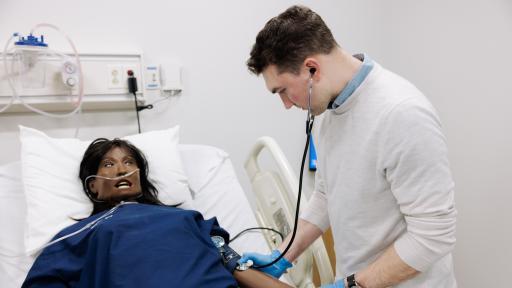 Student using stethoscope on mannequin patient in simulation lab 